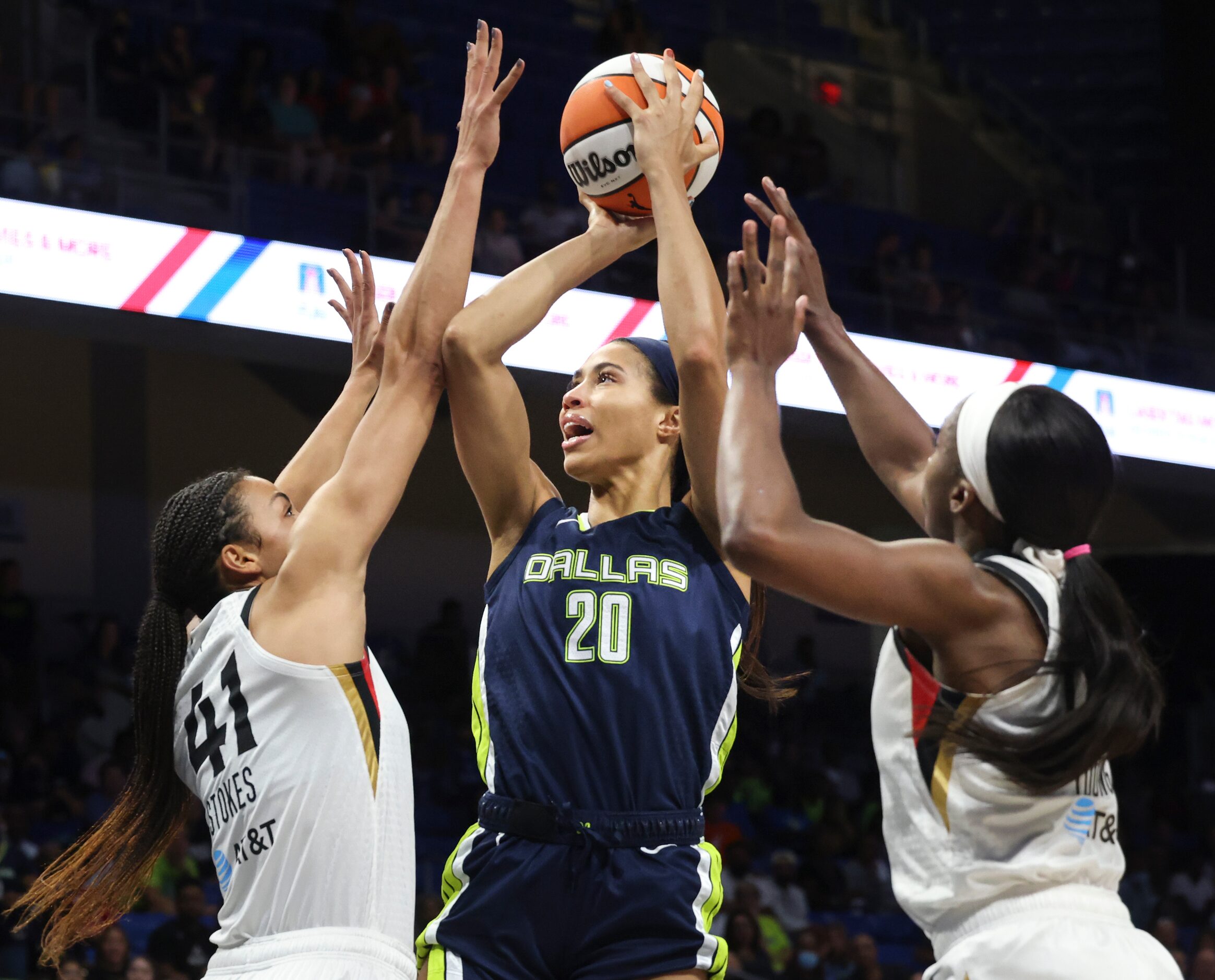 Dallas Wings forward Isabelle Harrison (20) splits Las Vegas Aces center Kiah Stokes (41)...