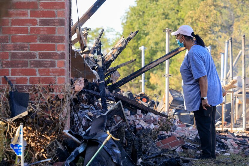 Glenda Jackson, 61, looks through a window of her home after a grass fire spread to her...