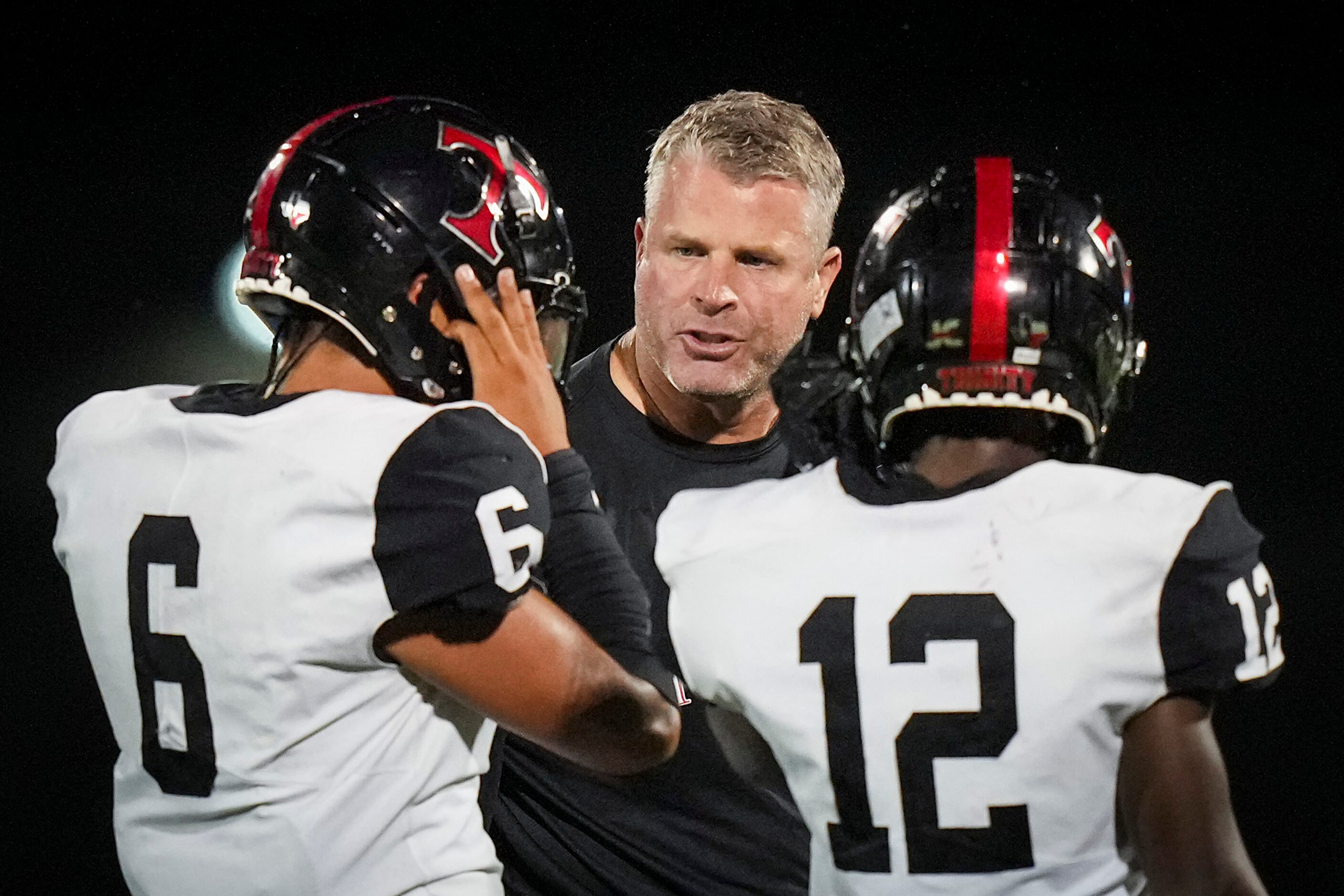 Euless Trinity head coach Aaron Lineweaver talks with linebacker Tupou Tupou (6) and...