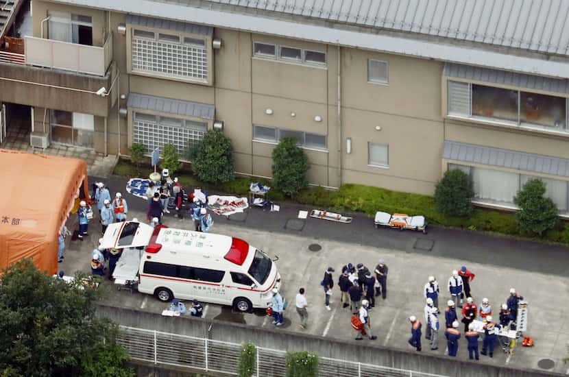 Ambulance crew and police officers  are seen outside a facility for the handicapped where a...