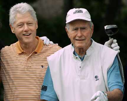 Former presidents Bill Clinton, left, and George H.W. Bush smile for wellwishers before...