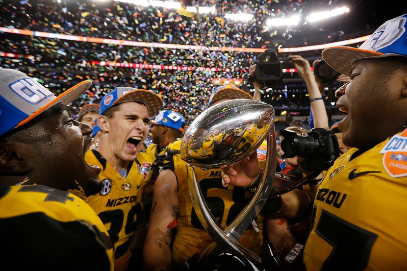 the Missouri Tigers football players celebrate with the winning trophy after defeating the...