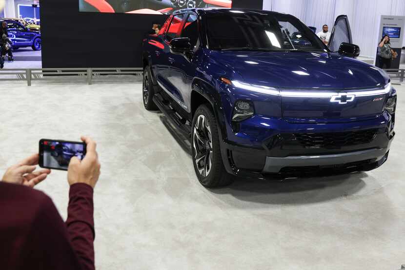 Phil Kwan takes a photo of a Chevy Silverado EV at the auto show at Fair Park on Sunday.