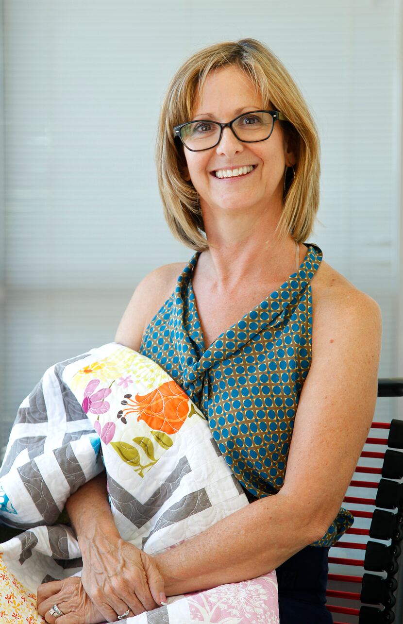 Michelle Kitto of Urban Spools Sewing Lounge cradles a modern quilt she made and named after...