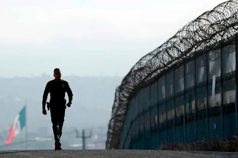 Agente camina por el muro entre San Diego y México./AP
