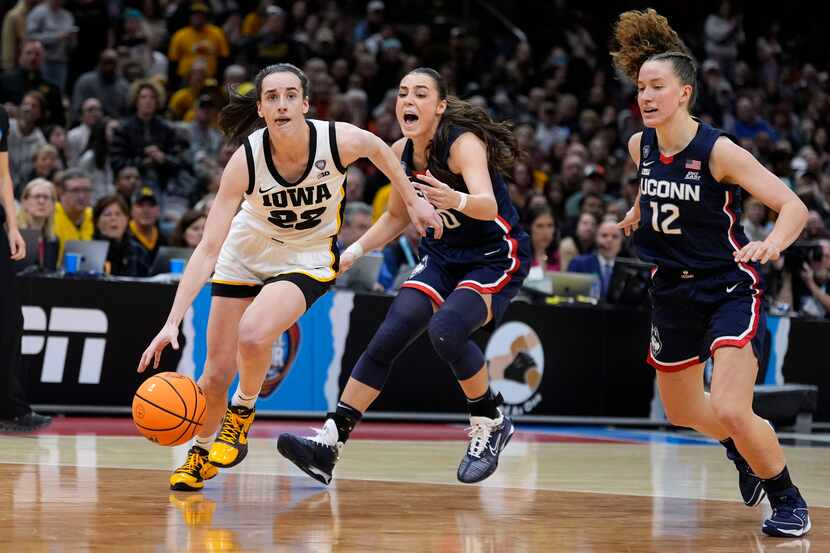 Iowa guard Caitlin Clark (22) drives to the basket past UConn guard Nika Muhl (10) and guard...