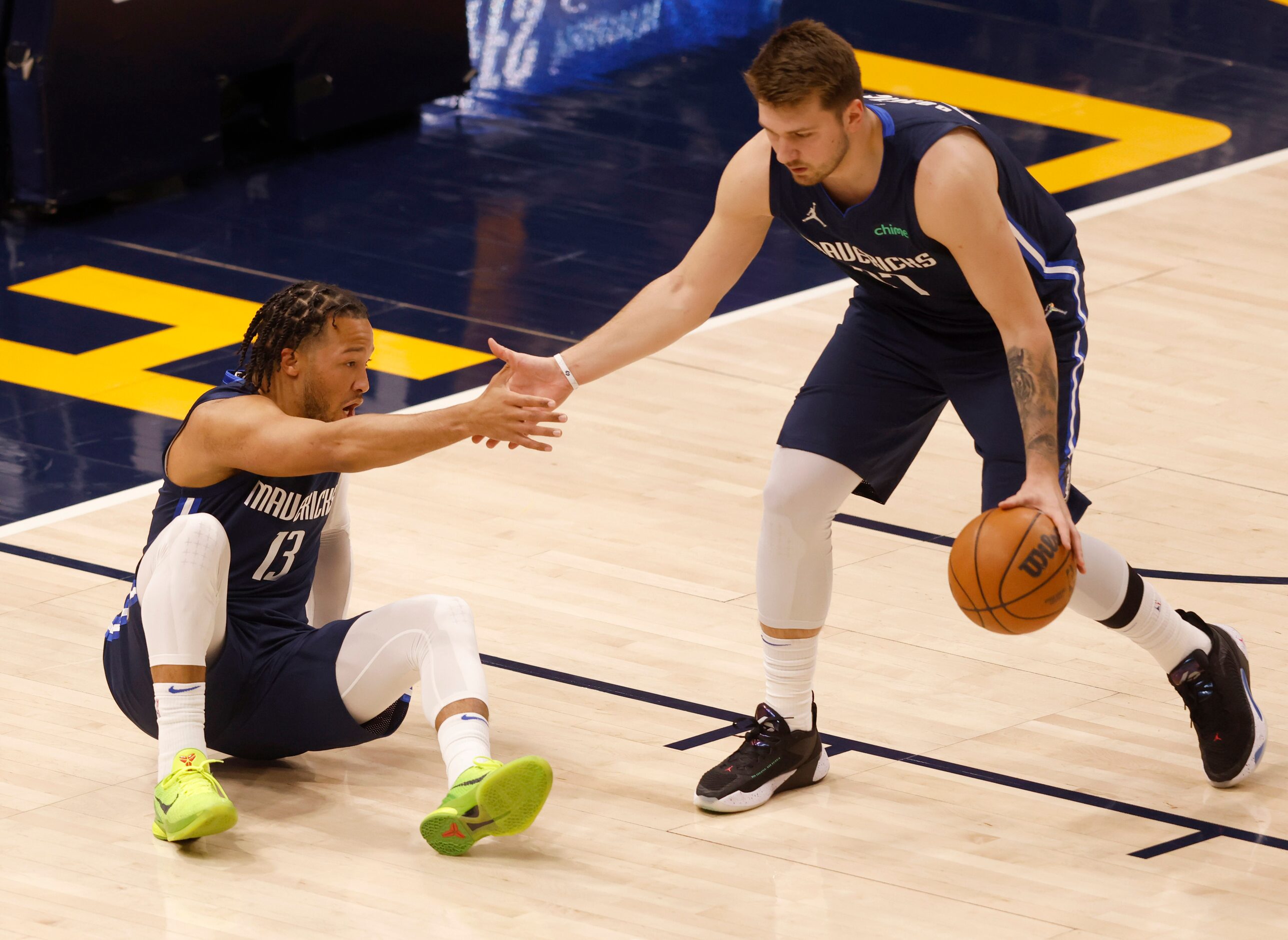 Dallas Mavericks guard Luka Doncic (77) helps up Dallas Mavericks guard Jalen Brunson (13)...