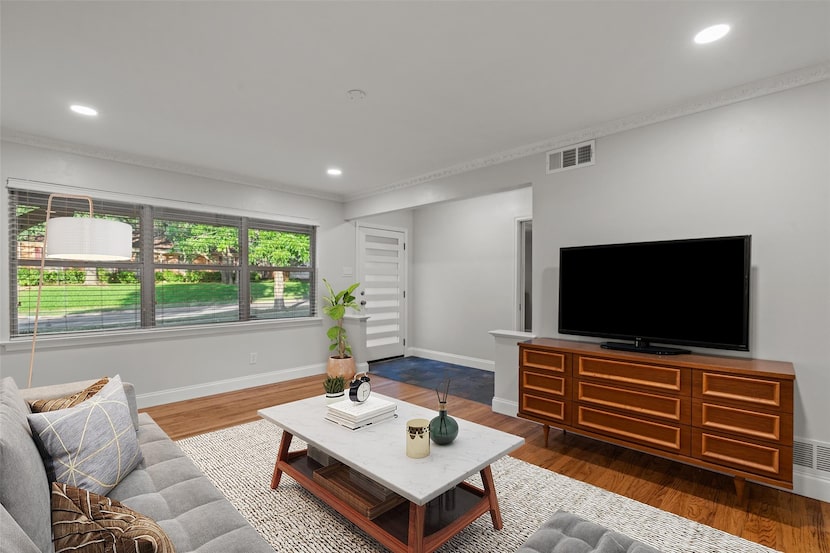 Room that has been virtually staged with TV, credenza, coffee table, rug, sofa and accessories