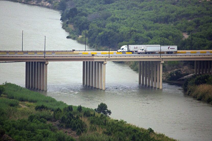 Trucks cross over the Laredo World Trade Bridge between Nuevo Laredo, Mexico (right) and the...