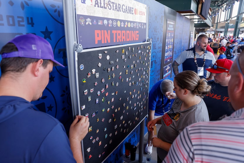 People trade pins on a board at the MLB All-Star Village inside Choctaw Stadium, Sunday,...