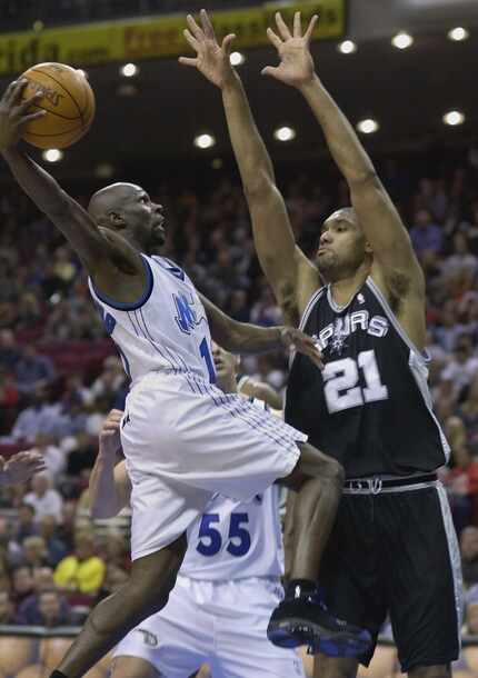 Orlando Magic's Darrell Armstrong (left) drives toward the outstretched arms of San Antonio...