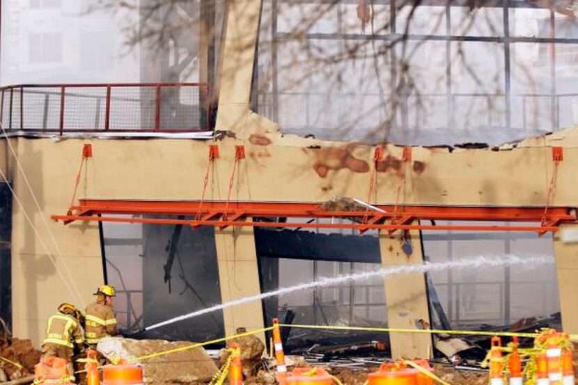 
Firefighters water down the remains of a two-story building in the Sylvan Thirty...