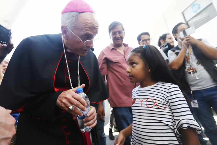 El Paso Bishop Mark Seitz prepares to escort Celsia Palma, 9, from Honduras, before they...