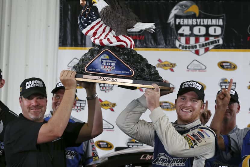 Chris Buescher, right, (34) holds up the winner's trophy with the help of President of...