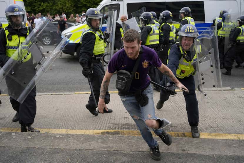 Police chased a protester outside the Holiday Inn Express in Rotherham, England, Sunday Aug....