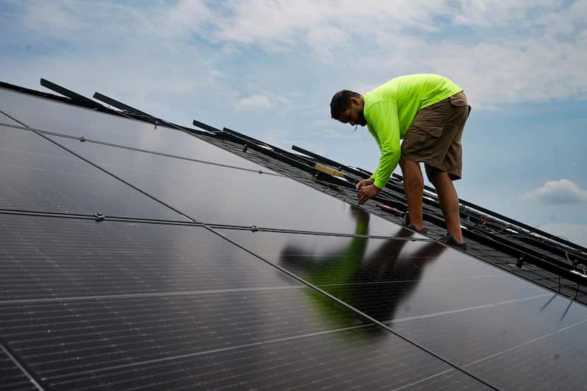 Nicholas Hartnett, owner of Pure Power Solar, secures solar panel on the roof of a home in...
