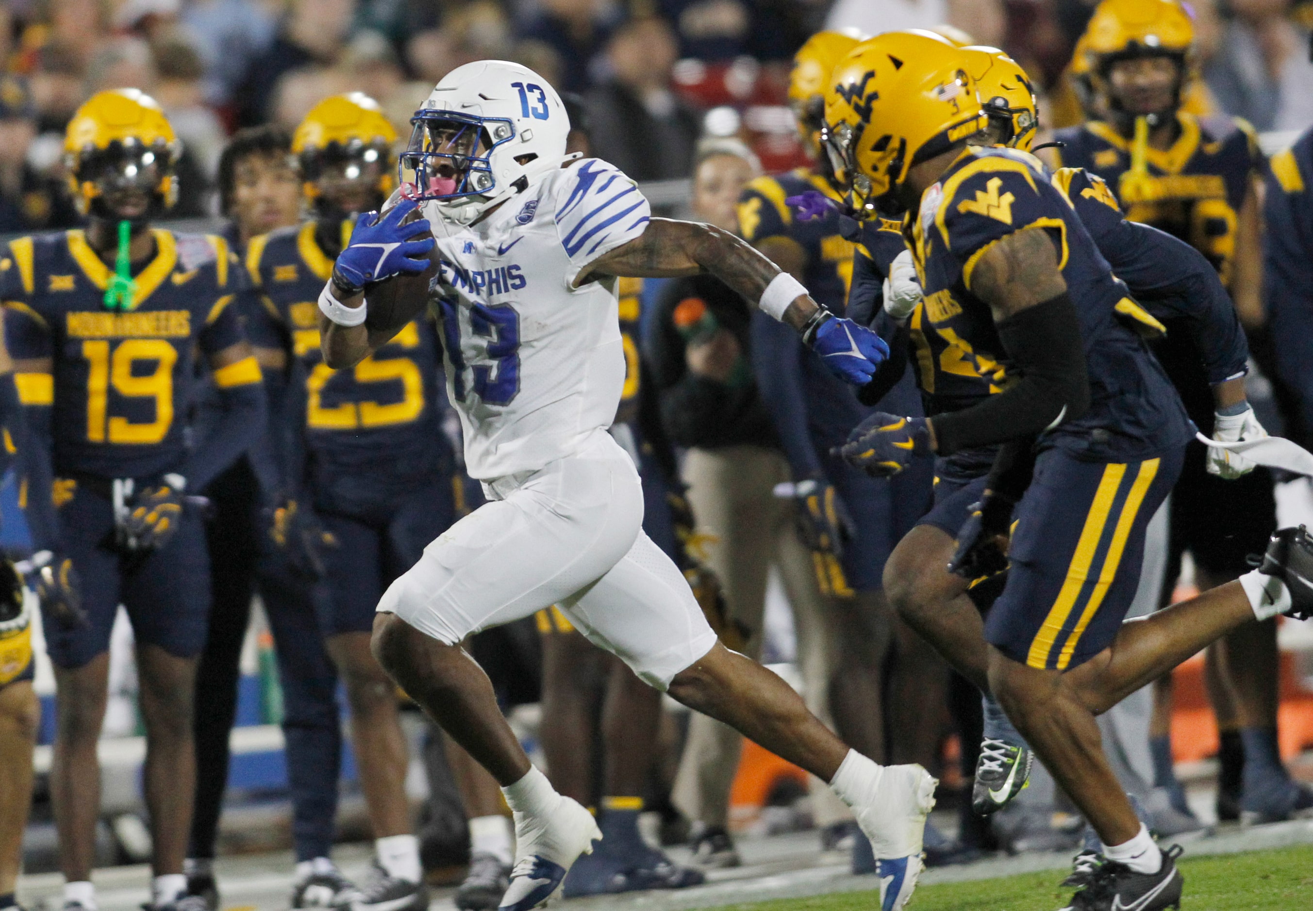 Memphis running back Greg Desrosiers (13) sprints past West Virginia defenders in front of...