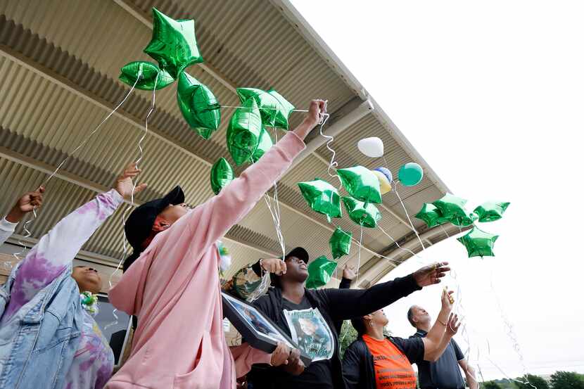 Roshone Jacob (center), mother of slain 16-year-old Ja'Shawn Poirier, releases green...