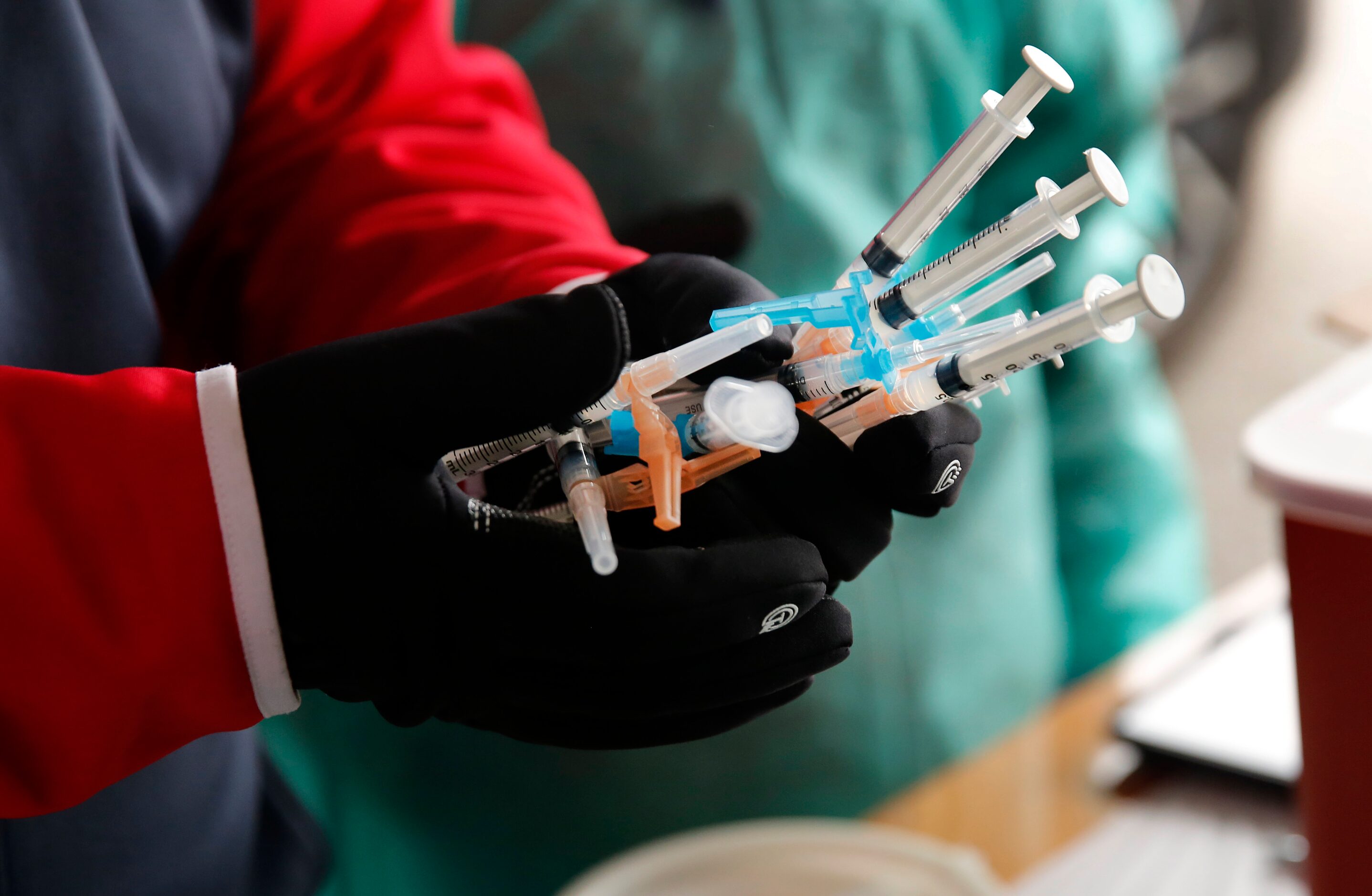 Handfuls of COVID-19 vaccinations are delivered to a drive-thru station at Fair Park in...