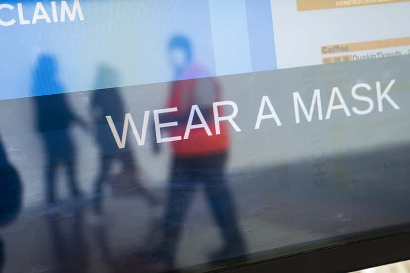 The arrivals board displays a message about wearing masks at Ronald Reagan Washington...