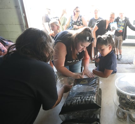 Autumn Hargett (left) passed a leopard gecko to Alicia Hall and 7-year-old Aaliyah Hall to...