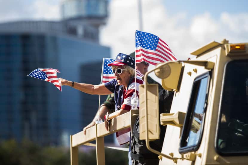 A woman waves an American flag from a military vehicle during the Dallas Veterans Day Parade...