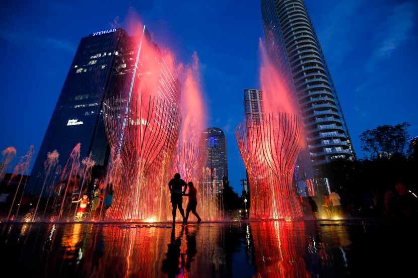 Children play in the Nancy Best Fountain while being unveiled with its first nightly water...