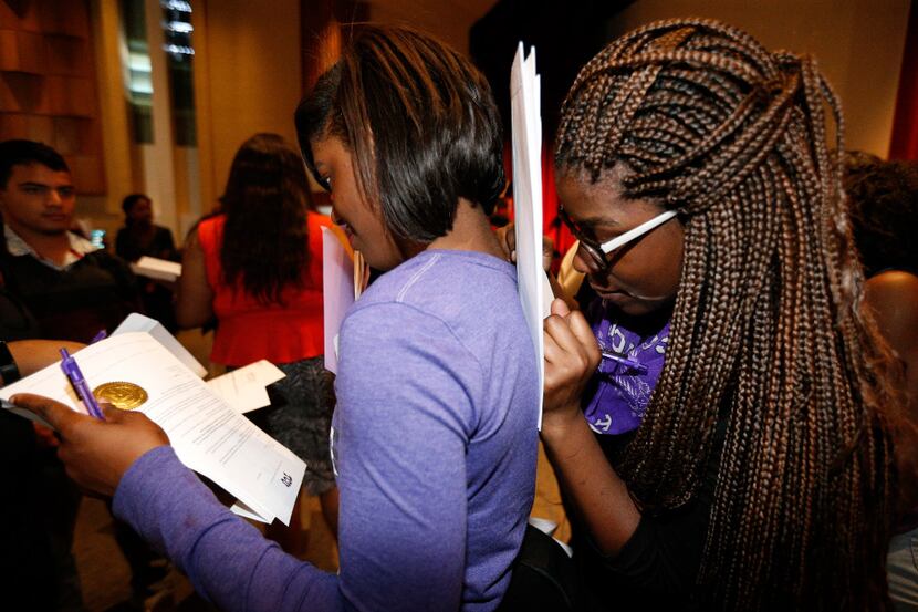 Nahjae Selby (right) signs paperwork on her twin sister, Tahjae Selby's, back after the...