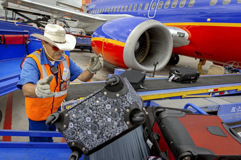 Southwest Airlines employee Frank Alfano unloads luggage from a plane at Dallas Love Field...