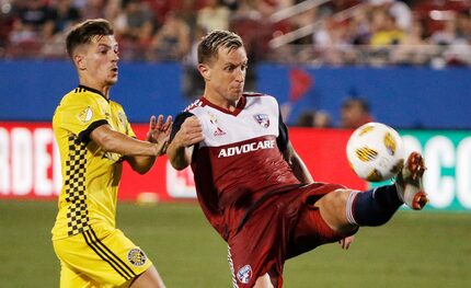 FC Dallas defender Reto Ziegler, right, plays the ball away from Columbus Crew midfielder...