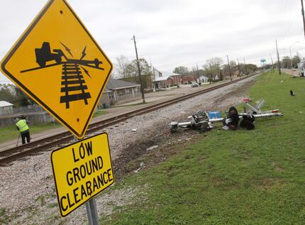 Debris from the railroad crossing signal litters the north side of the railroad tracks on...