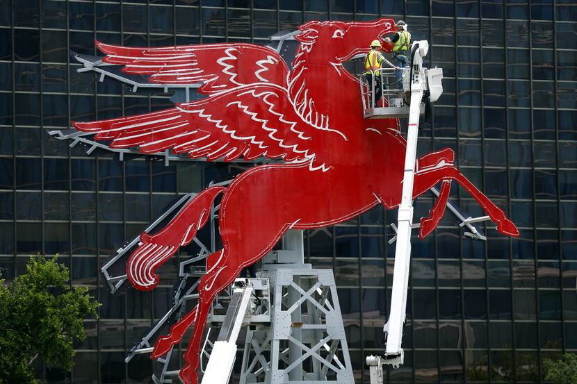 Starlite Sign installers Brach Daniel, left, and Ray Allen wire the original red Pegasus...