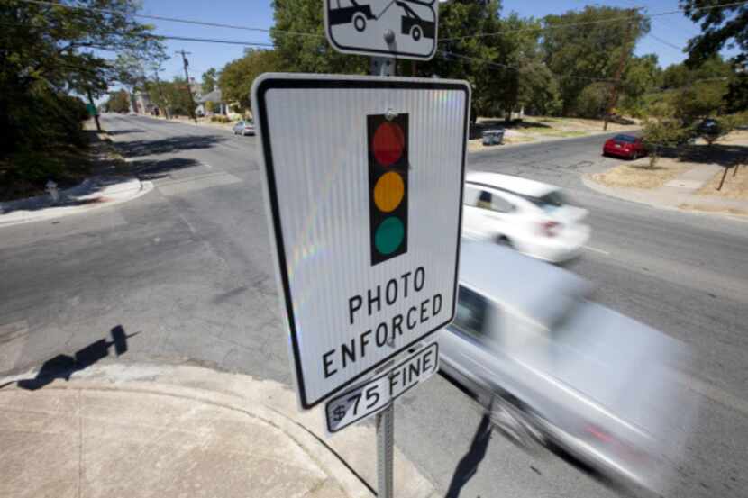 A sign warns drivers on Peak Street of red-light traffic cameras at an approaching...