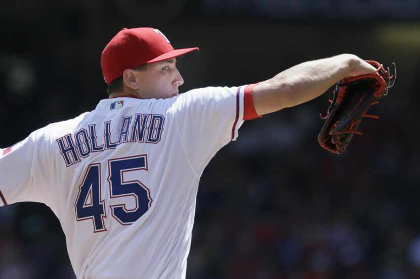 Texas Rangers starting pitcher Derek Holland throws during the first inning of a baseball...