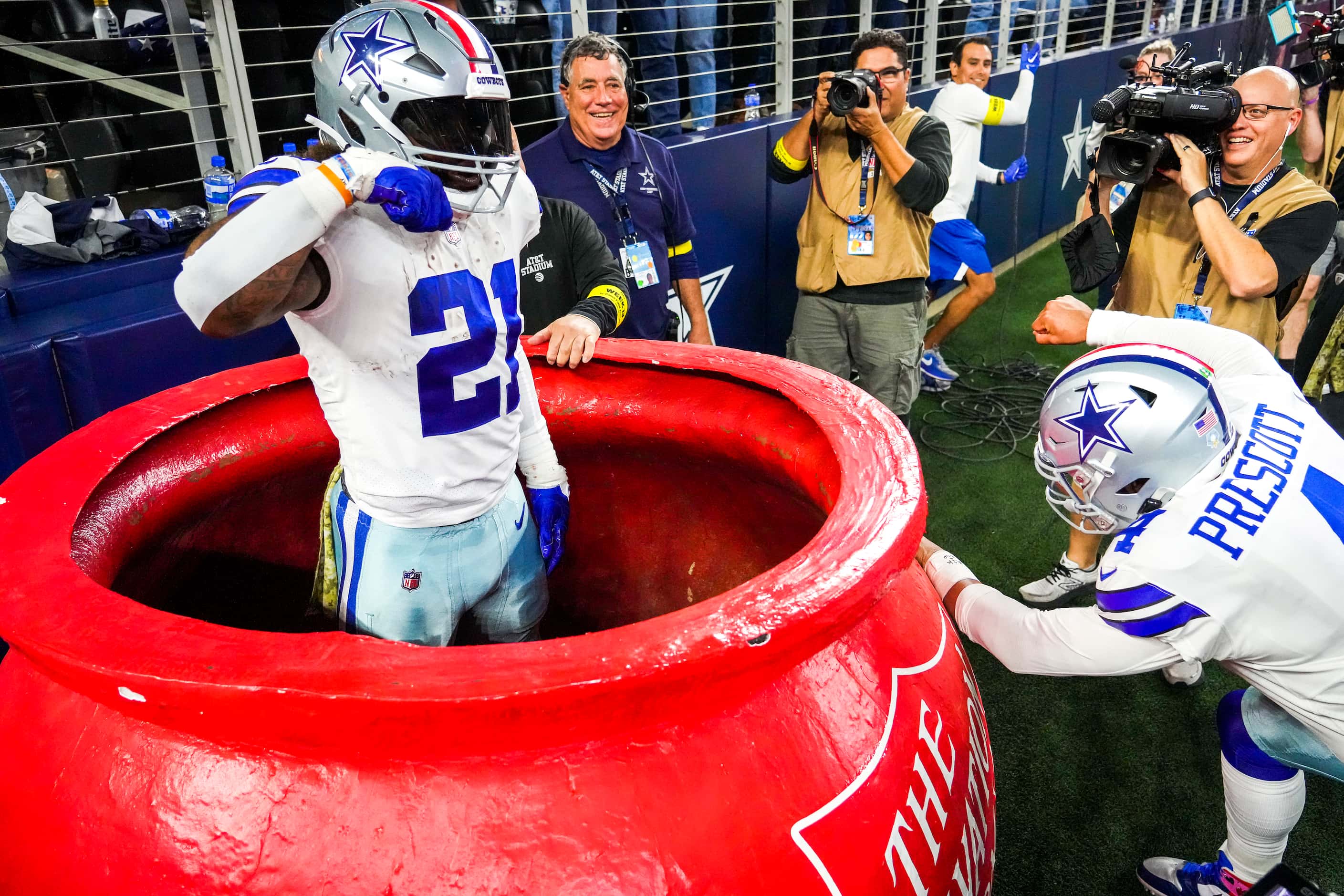Dallas Cowboys running back Ezekiel Elliott (21) pops out of a Salvation Army kettle as...