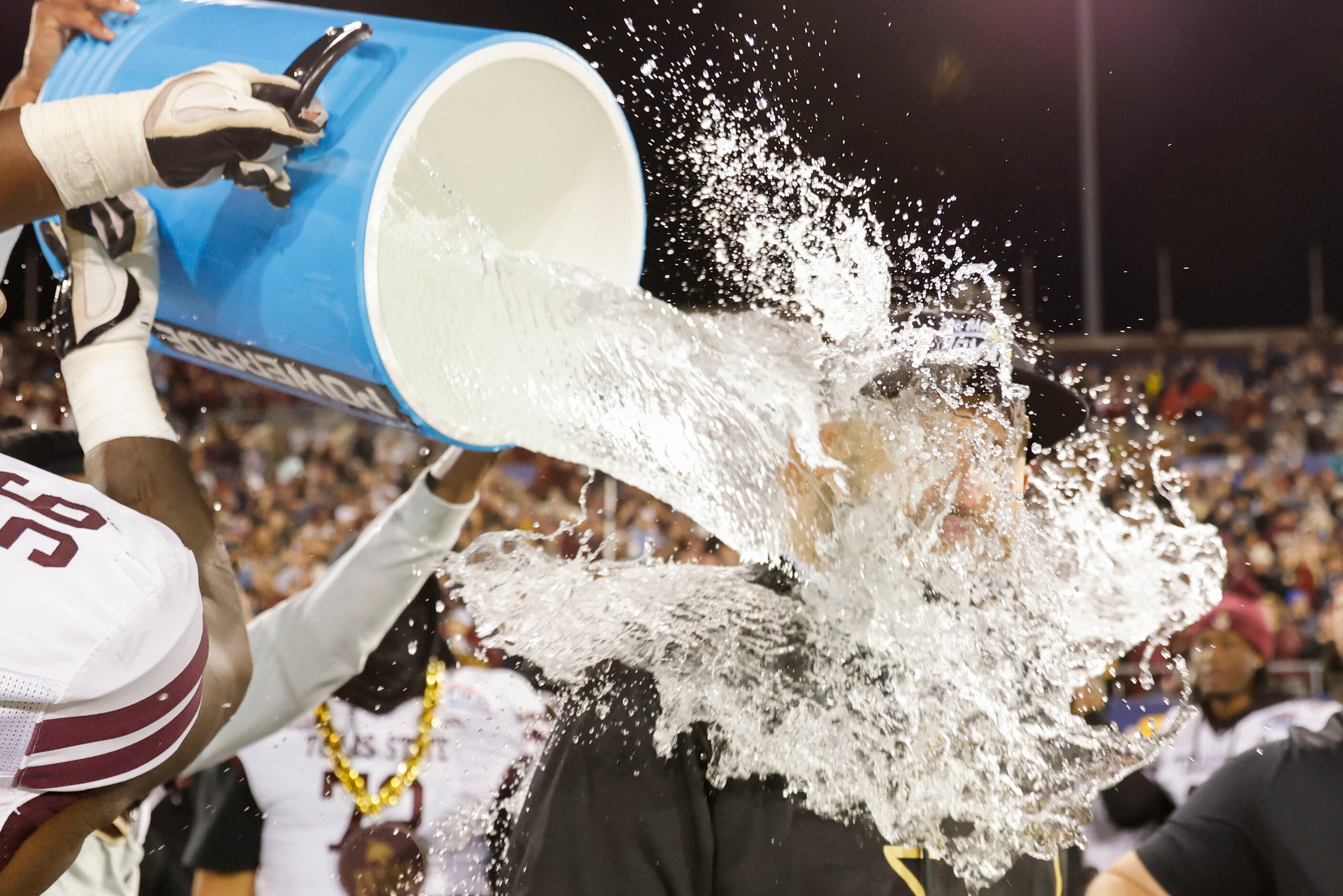 Texas State head coach GJ Kinne is doused by water ahead of his team’s victory in the First...