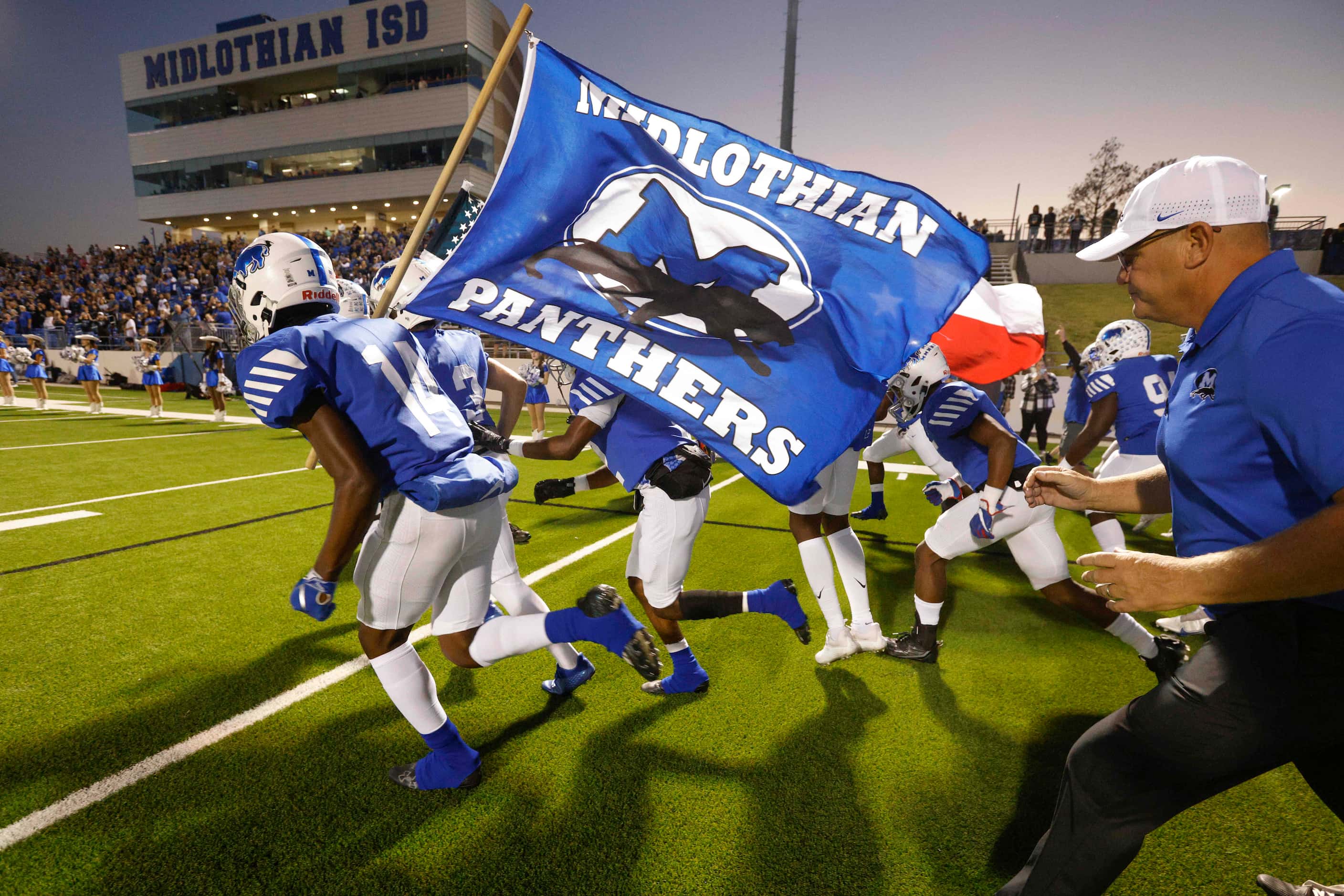 Midlothian wide receiver Quintin Bradley (14)carries a flag as he leads the team onto the...