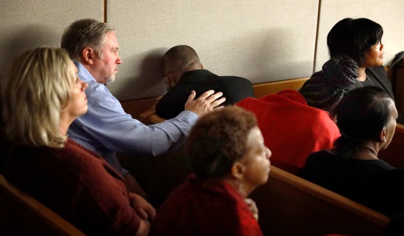 Outside the presence of the jury, Botham Jean's father, Bertrum Jean (center), leans his...