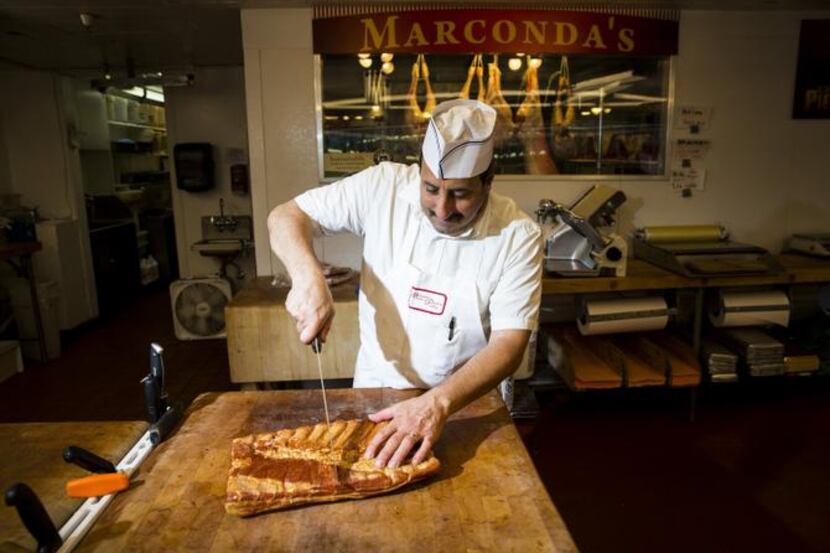 
Lou DeRosa, Marconda’s Meats owner, cuts a slab of Danish pork belly in half. Besides its...