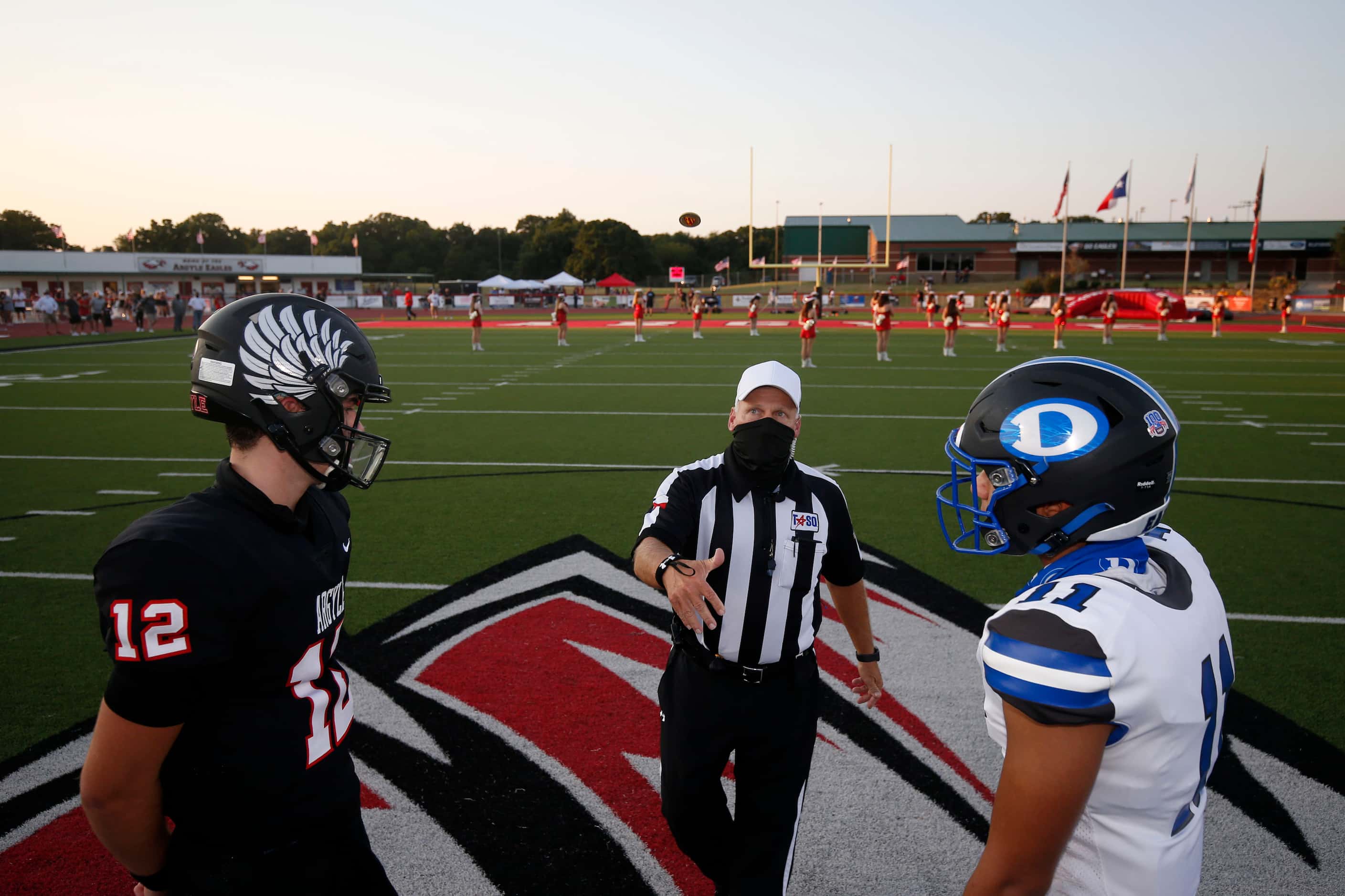 Referee Dan Wroe wears a face covering while flipping a coin in front of Argyle quarterback...
