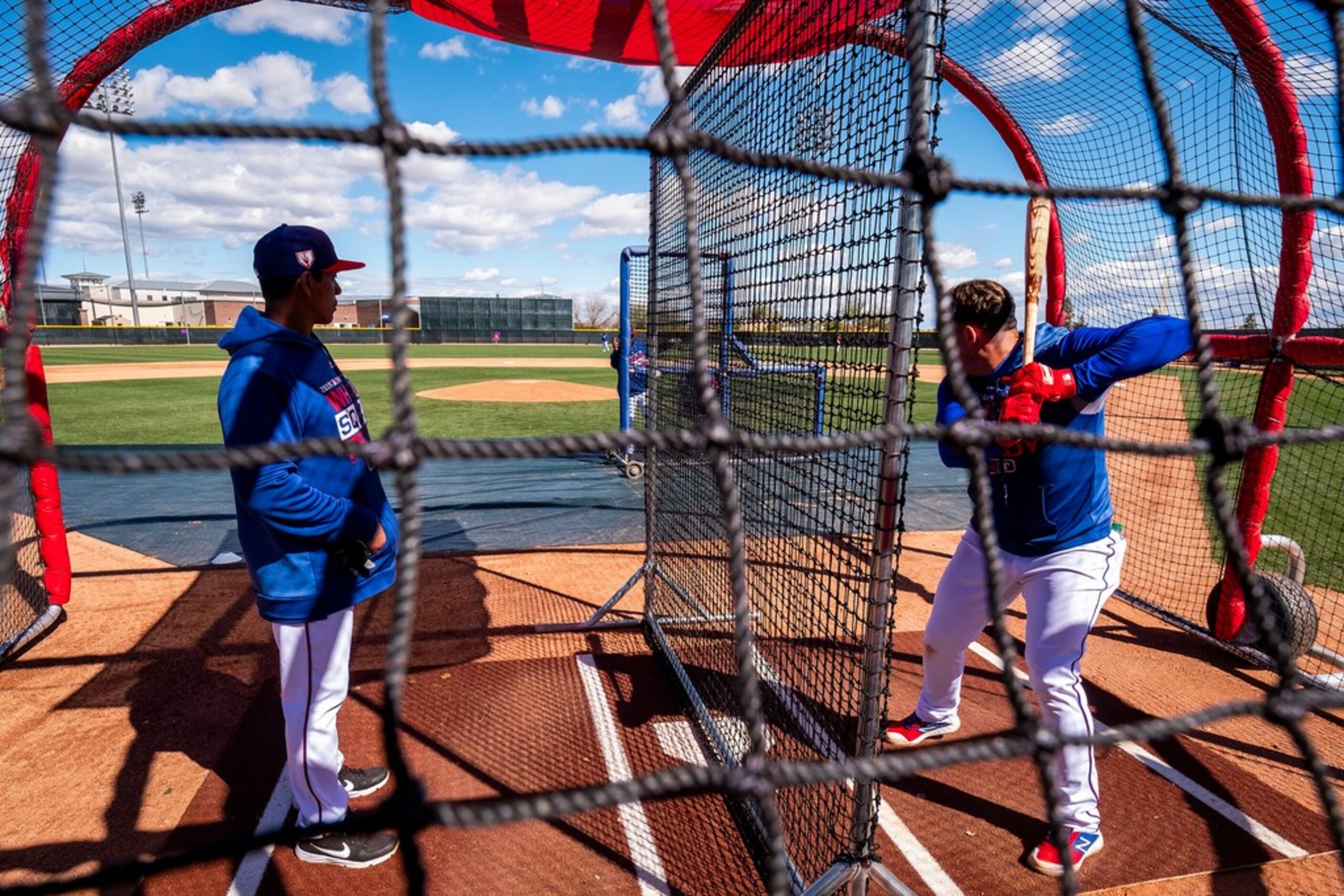 Texas Rangers hitting coach Luis Ortiz works in a batting cage with infielder Asdrubal...