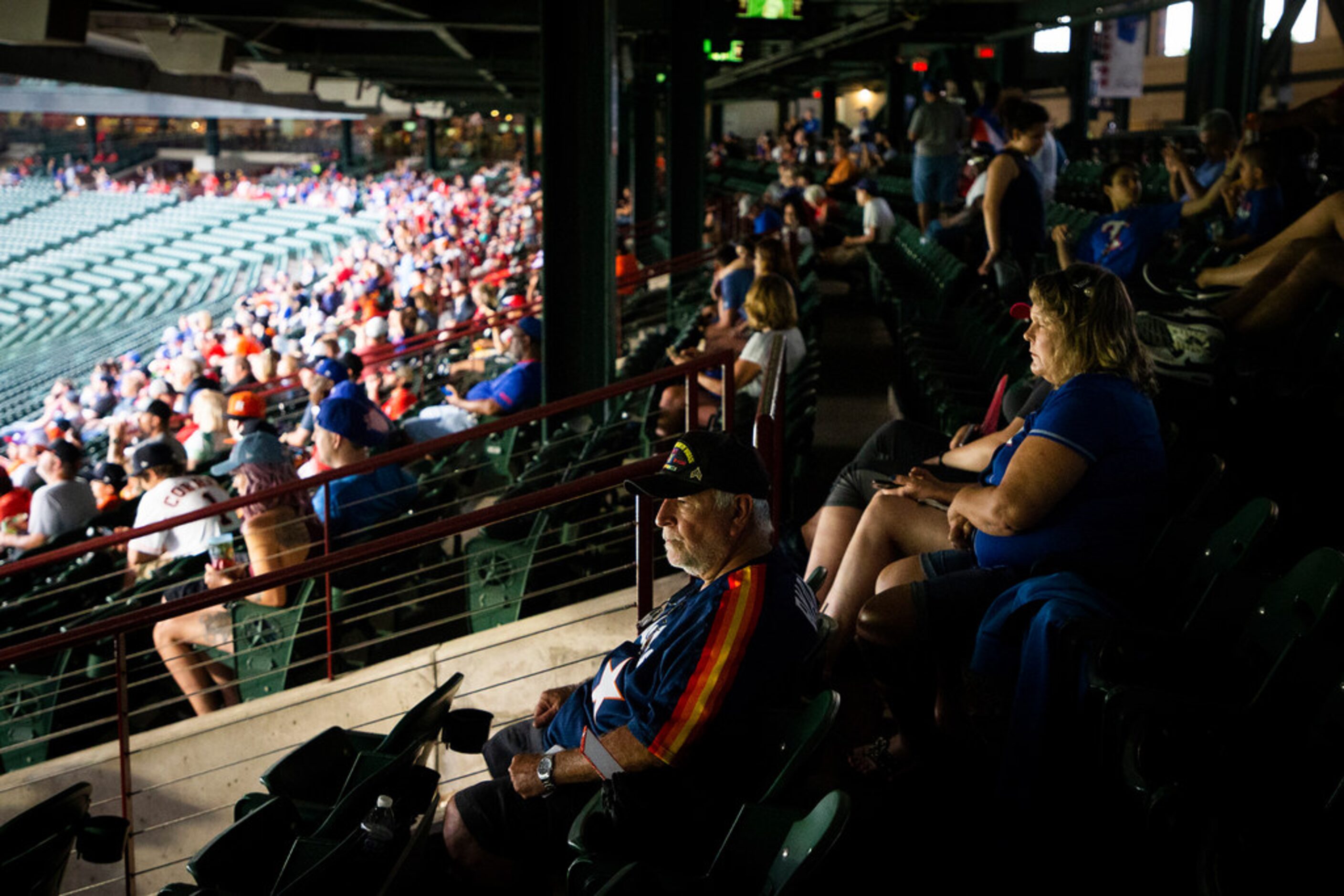 Fans take cover during a rain delay before a baseball game between the Texas Rangers and the...