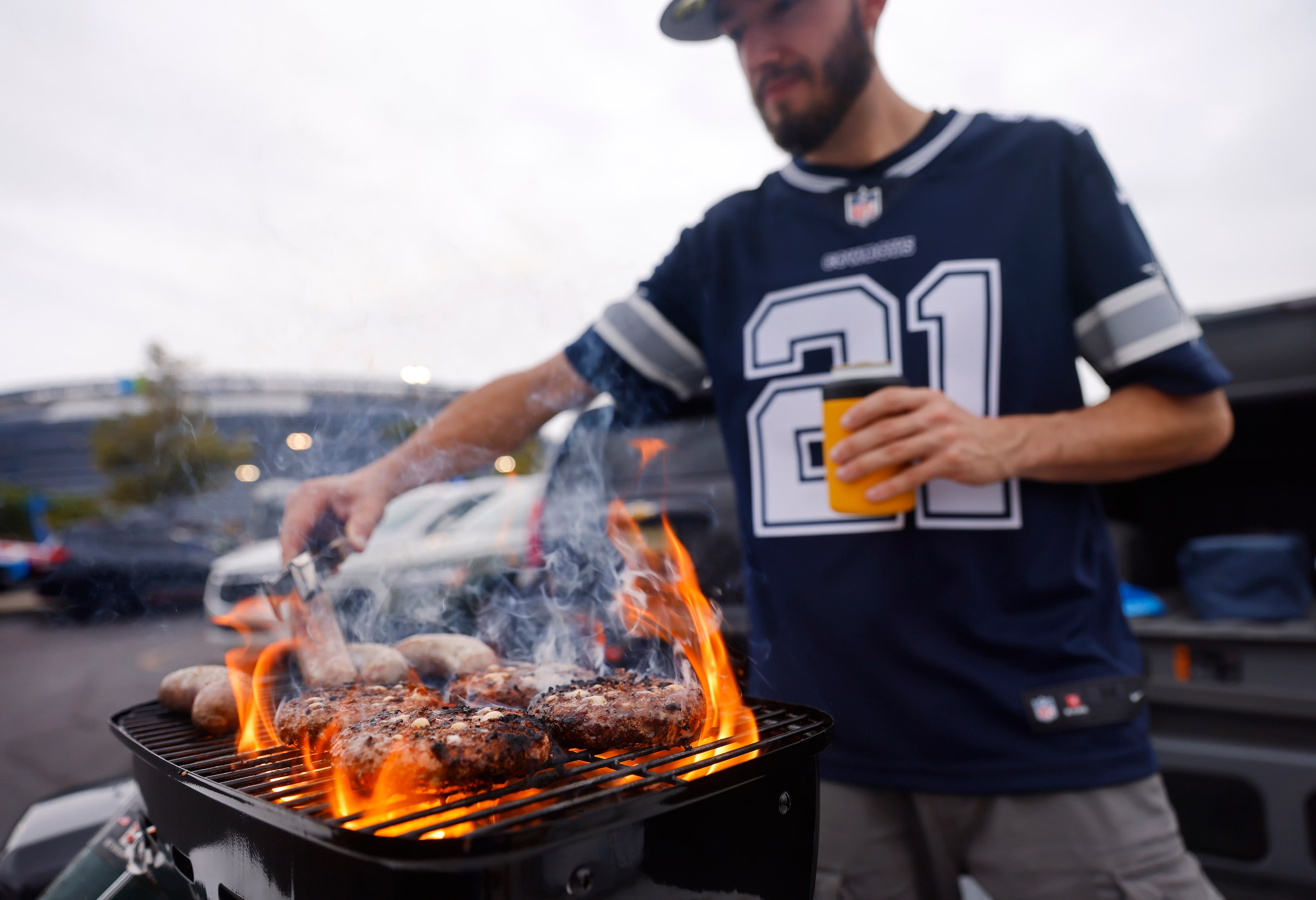 Dallas Cowboys fans Corey Casterline of Wilkes-Barre, Pennsylvania grills hamburgers and...