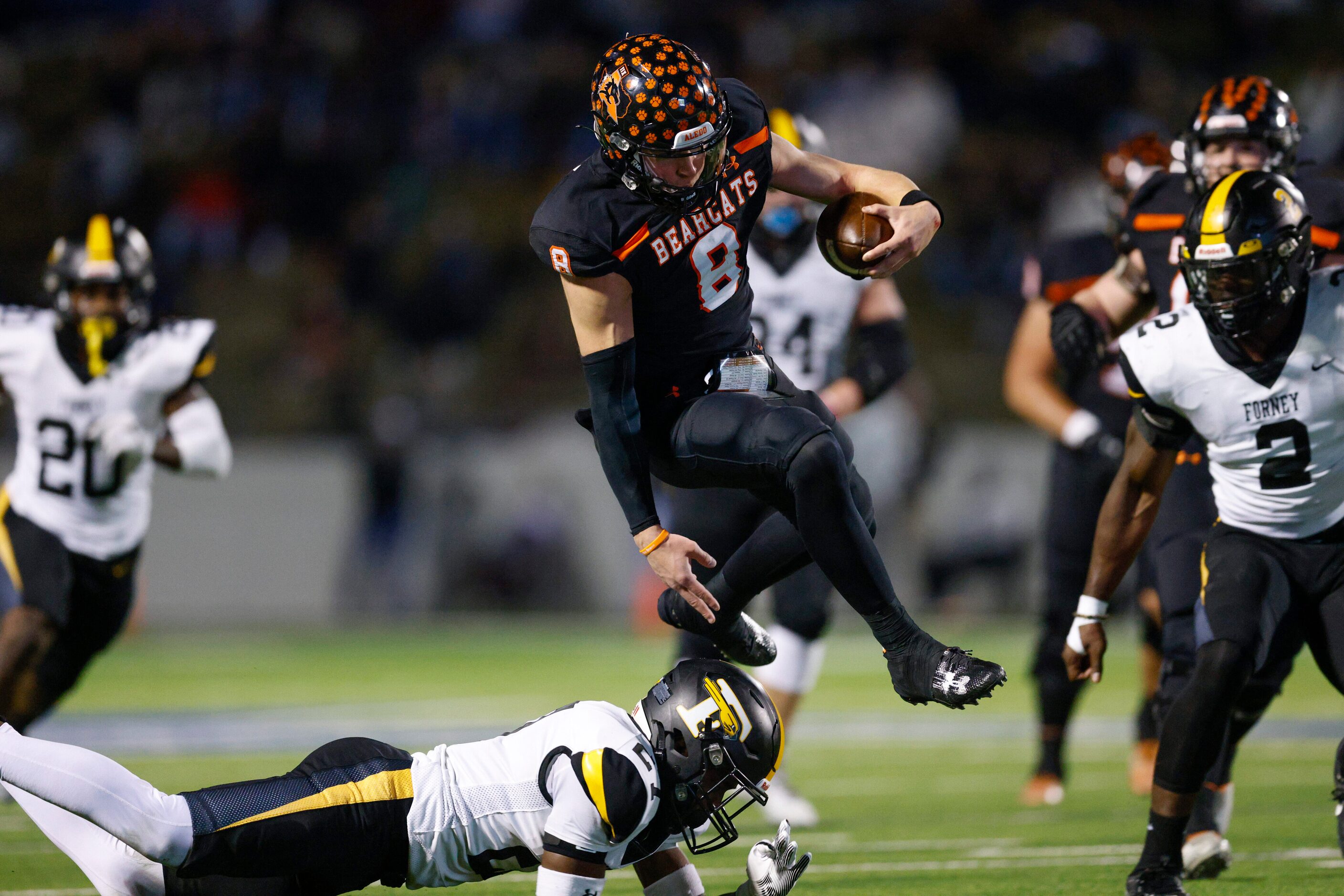 Aledo quarterback Hauss Hejny (8) leaps over Forney defensive back Josiah Turner (27) during...