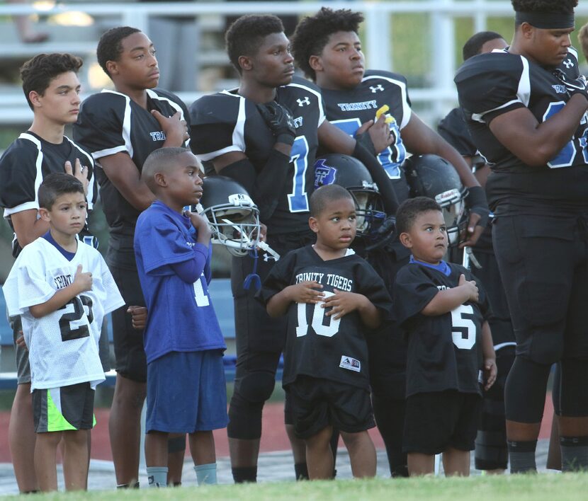 Members of the Trinity Christian football team are joined by young fans on the sideline...