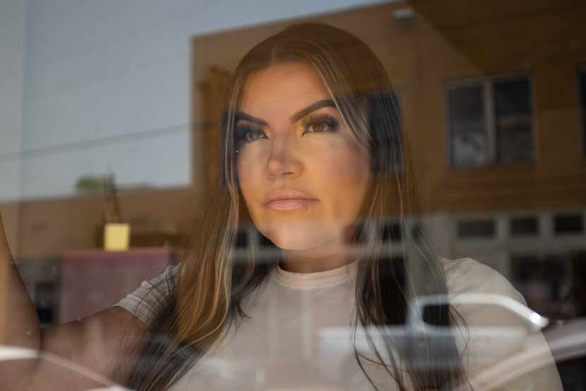Diana Vasquez, 34, is reflected through the store front glass of her business Beauty and...