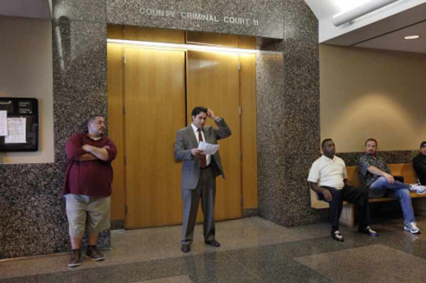 People wait outside a courtroom at Dallas County’s Frank Crowley Courts Building. A...