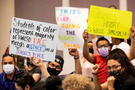 Community members in support of equity conversations in schools held signs on Tuesday during...