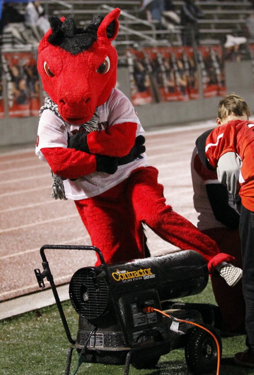 The Mansfield Legacy High mascot warms it's foot using a gas heater on the sideline during a...