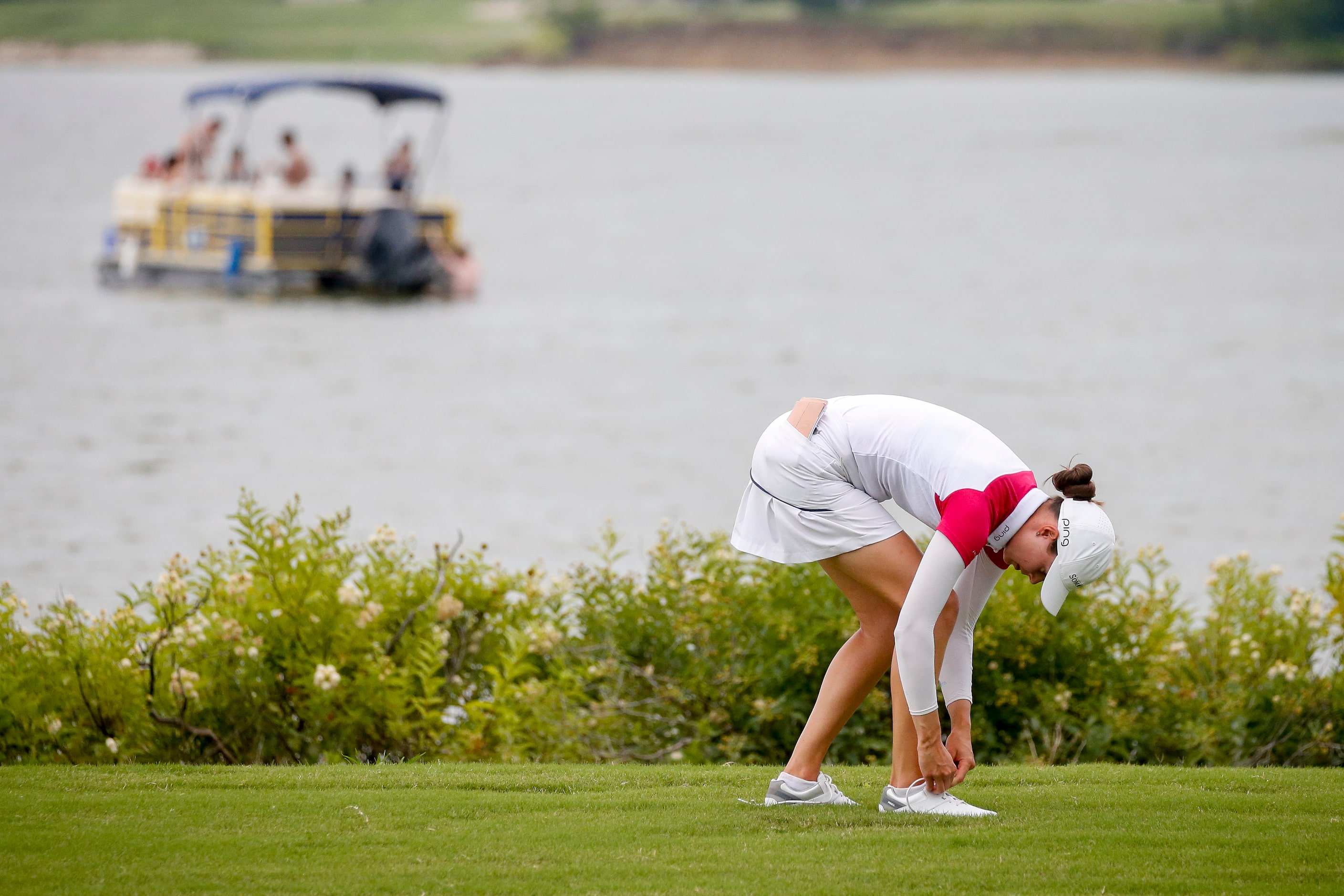 Professional golfer Esther Henseleit ties her shoe on the No. 12 fairway after hitting a...